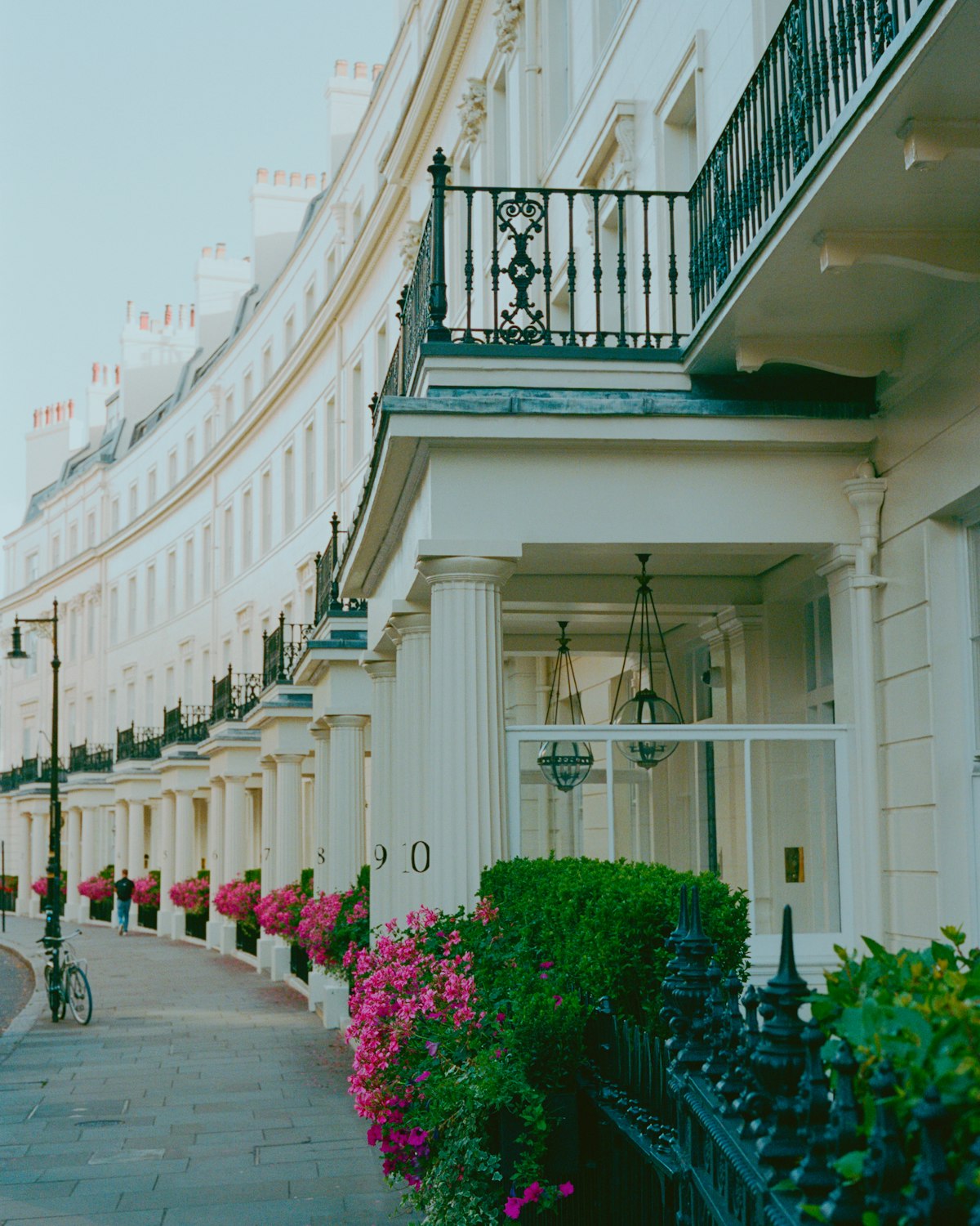 A curved terrace of white stucco houses with balconies and flowering window boxes