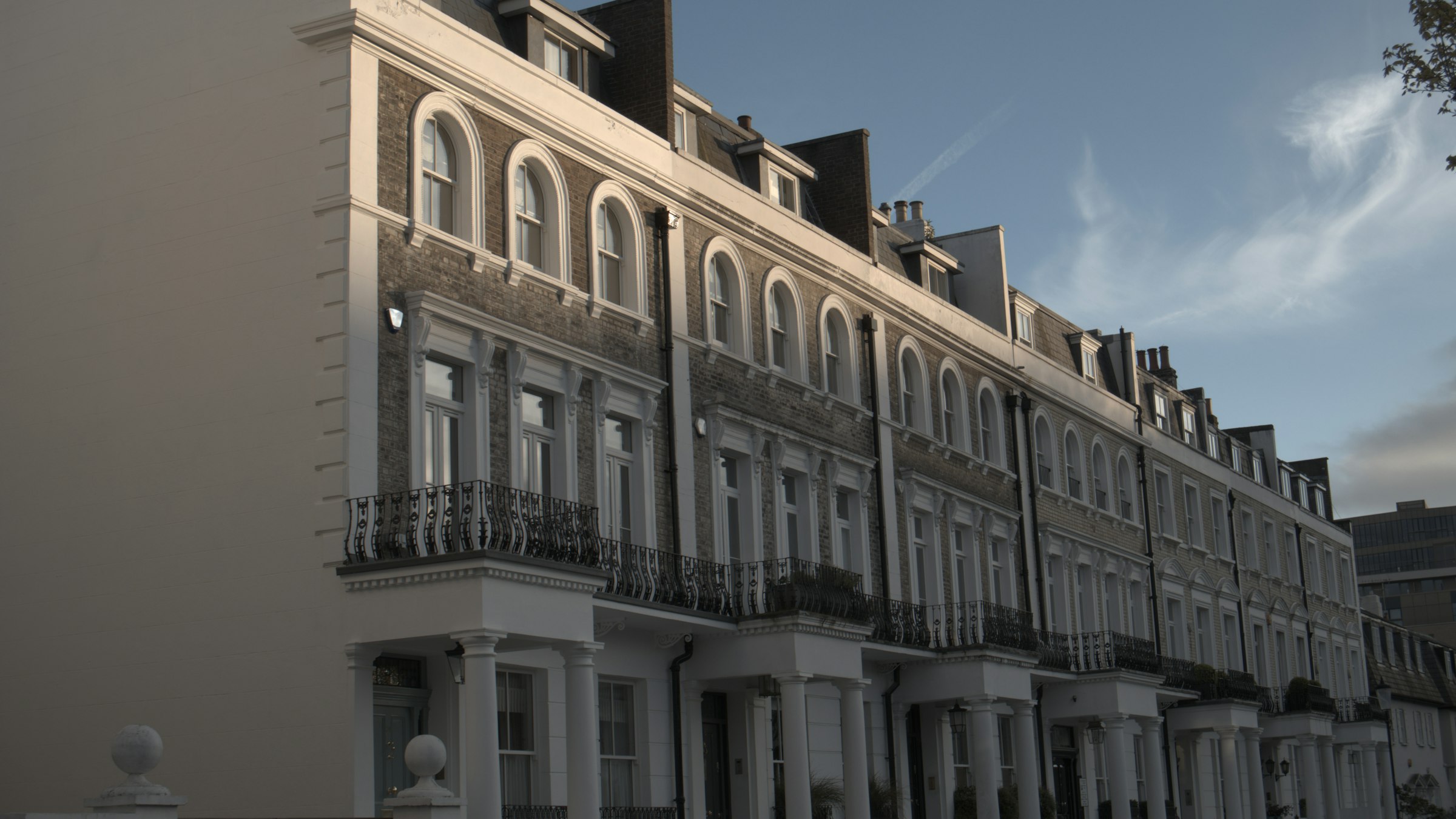 A terrace of white stucco townhouses in London in the evening light